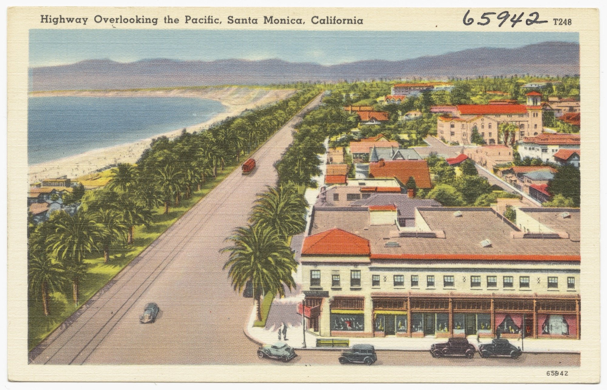 Colour-tinted linen postcard of Santa Monica: a palm-lined coastal highway curving along the shore, with commercial buildings and red-tiled roofs in the foreground.